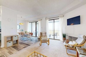 A spacious living room with a dining area, a fireplace, and large windows. - Our Place At The Beach 304C (Ocean City)
