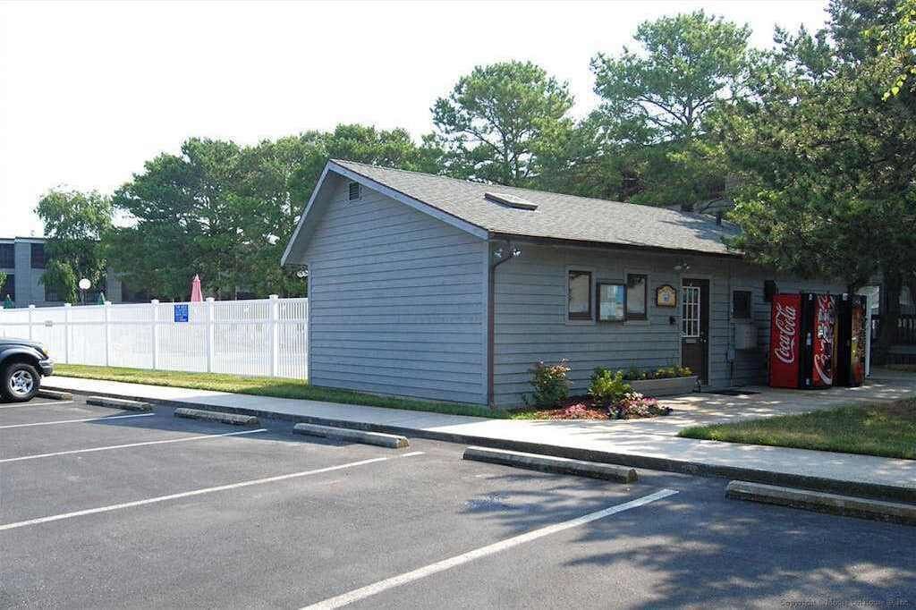 A small building with a sloped roof, a Coca-Cola vending machine, and a parking lot.