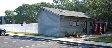 A small building with a sloped roof, a Coca-Cola vending machine, and a parking lot.