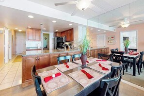 A modern kitchen with wooden cabinets, a central island, and a dining area with a table set for four. - Marvelous beach condo with balcony, pools, gym, sauna & game room (Ocean City)