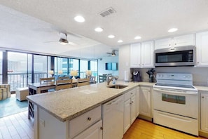 A modern kitchen with white cabinets, a granite countertop, a built-in microwave, and a double oven. - Beachfront corner condo with balcony, views, pools, game room, gym & sauna (Ocean City)