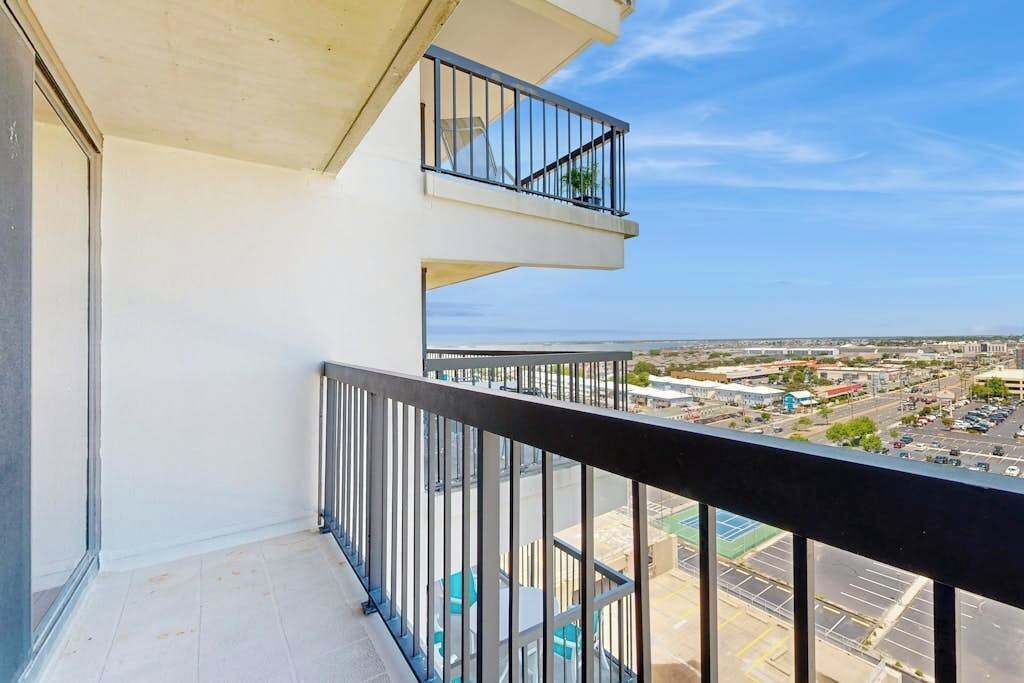 Ein Balkon mit Blick auf eine Stadtlandschaft, einem Geländer und einem wolkenlosen Himmel.