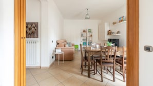 A room with a dining table, chairs, a sofa, a radiator, and a shelf with books and decorative items. - D Ossuna Central Home by Wonderful Italy (Palermo)