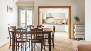 A dining area with a wooden table and chairs, a kitchen in the background, and a sliding glass door leading outside. - D Ossuna Central Home by Wonderful Italy (Palermo)