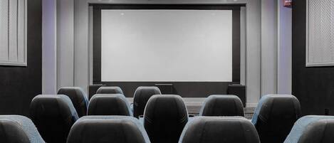 A conference room with a large screen, rows of chairs, and a podium.