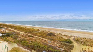 Een strand met heldere lucht, zandstrand en begroeiing.