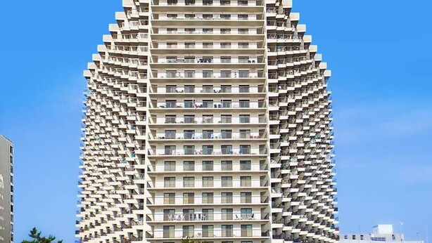 A high-rise building with a unique angular design, featuring multiple balconies and a uniform facade. - Ocean-view getaway with balcony, AC, pools, saunas, tennis & gym (Ocean City)