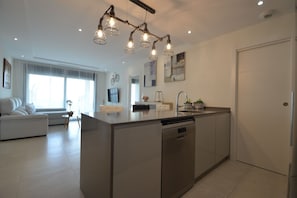 Eine moderne Küche mit Kochinsel, Essbereich mit einer Couch und einem großen Fenster.