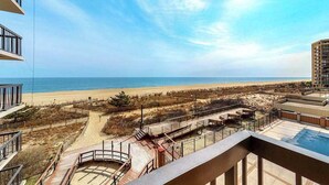 A beachfront property with a pool, outdoor seating, and a view of the beach. - Sunny coastal condo with beach views, balcony, pools, gym, sauna & AC (Ocean City)