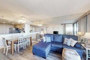 A modern living room with a sofa, ottoman, and dining area. - Convenient Beach Condo w/Private Balcony, Shared In/Outdoor Pools, Gym, Sauna (Ocean City)