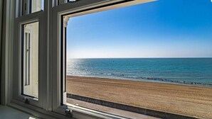 Une fenêtre donnant sur une plage et l’océan.