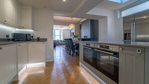 Une cuisine moderne dotée d’un îlot central, d’appareils électroménagers intégrés et d’un coin repas offrant une vue agréable.