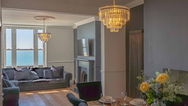 Un salon moderne avec un canapé, une table à manger et un lustre.