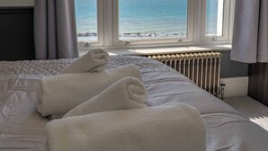 Une chambre avec vue sur la mer, un lit avec des serviettes pliées et un radiateur.