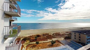 A coastal building with balconies overlooking a beach and ocean. - Updated, oceanfront condo with furnished balcony, fast WiFi, central AC & pool (Ocean City)