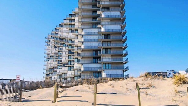 A multi-story building with balconies, located near a sandy area. - Updated, oceanfront condo with furnished balcony, fast WiFi, central AC & pool (Ocean City)