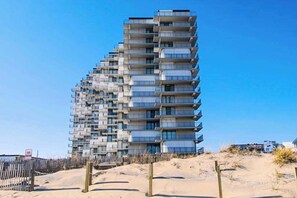 A multi-story building with balconies, located near a sandy area. - Updated, oceanfront condo with furnished balcony, fast WiFi, central AC & pool (Ocean City)