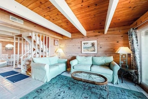 Ein Holzinnenraum mit einer Treppe, zwei hellem Sofas, einem Couchtisch und einem Essbereich.