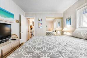 Hotellihuone, jossa on sänky, televisio, työpöytä ja vaatekaappi.