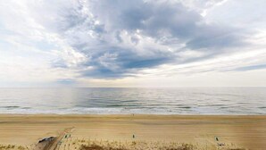 Ein Strand mit sandigem Ufer, einigen Stühlen und einer Umzäunung.