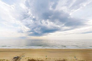 Ein Strand mit sandigem Ufer, einigen Stühlen und einer Umzäunung.