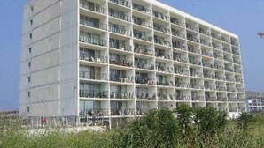 Ein mehrstöckiges Hotel mit Balkonen, einer glatten Fassade und blauem Himmel.