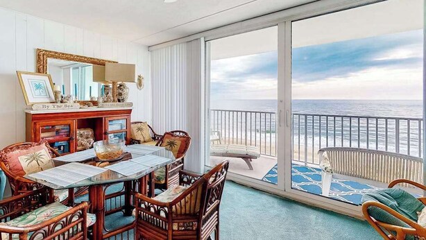 Ein Balkon mit Meerblick, ein Essbereich mit Tisch und Stühlen sowie ein großes Spiegelbild an der Wand.