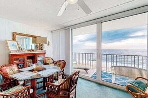 Ein Balkon mit Meerblick, ein Essbereich mit Tisch und Stühlen sowie ein großes Spiegelbild an der Wand.