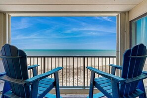 A balcony with two blue Adirondack chairs facing a beach. - Sandpiper Dunes 504 (Ocean City)