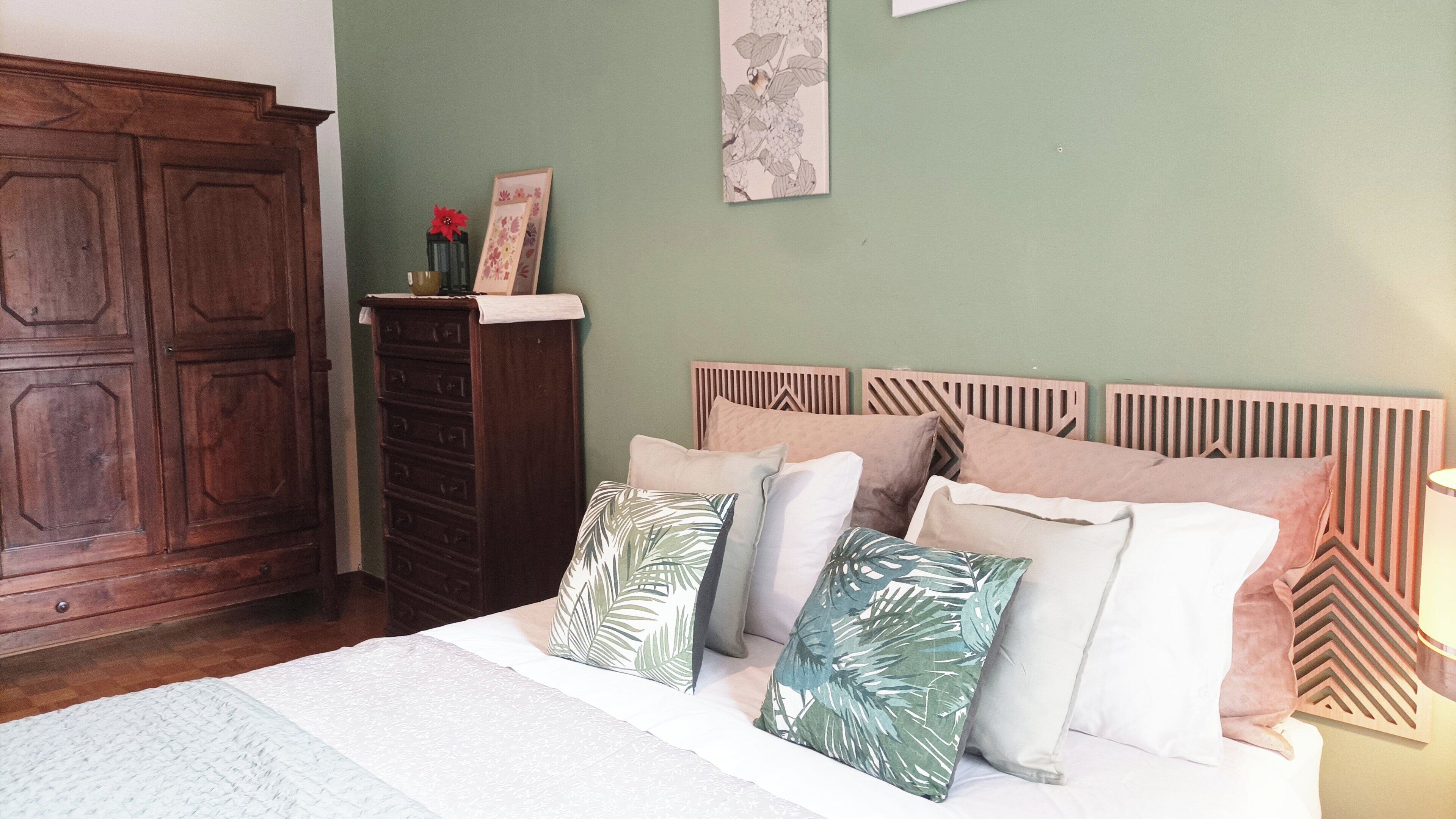 A bedroom with a bed, wooden headboard, and a nightstand with a lamp.