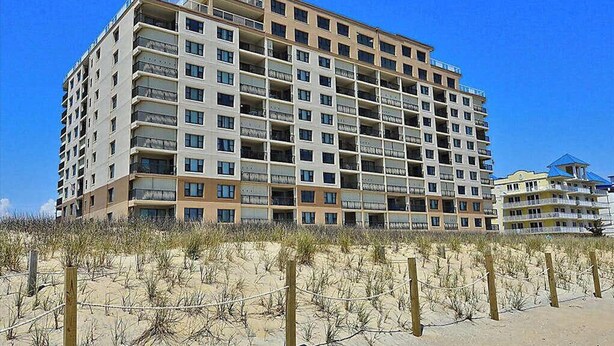 A multi-story hotel with balconies, located near a sandy beach. - Sandpiper Dunes 212 (Ocean City)