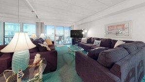 A living room with a sofa set, a TV, and a glass coffee table. - Sandpiper Dunes 212 (Ocean City)