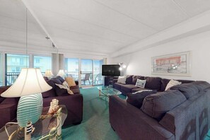 A living room with a sofa set, a TV, and a glass coffee table. - Sandpiper Dunes 212 (Ocean City)