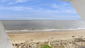 A beach view from a balcony with a clear sky. - Oceanfront Condo with a Shaded Balcony, AC, WiFi, Laundry & Shared Pool (Ocean City)