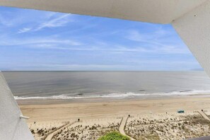 Blick auf einen Strand von einem Balkon bei blauem Himmel.
