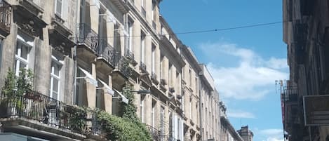 Une rangée de bâtiments historiques dotés de balcons, une enseigne indiquant « Antiquités et brocante », et une enseigne « mimilio ».