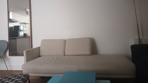 Ett vardagsrum med en soffa, ett soffbord, en lampa och en stol.