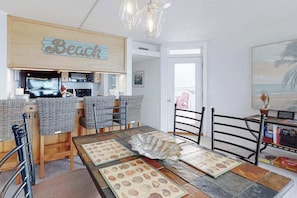 Een kamer met een strandthema, voorzien van een keukenhoek, een eettafel met placemats, en uitzicht op het strand.