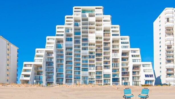 Ein mehrstöckiges Hotel mit moderner Architektur, mit Balkonen und direkt am Strand gelegen.