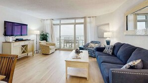 Ein Wohnzimmer mit Sofa, Couchtisch, Fernseher und einem Balkon mit Blick.