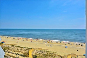 A beach with a clear sky, a sandy shore, and a fence in the foreground. - Oceanfront Condo with a Balcony, Beach Views, AC, WiFi & Shared Outdoor Pool (Ocean City)