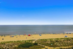 Ein Strand mit Sonnenschirmen, einigen Zelten und einem Weg zum Wasser.