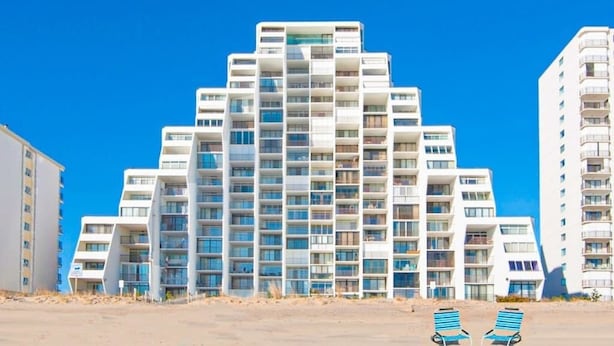 Ett modernt hotell med flera våningar och en unik arkitektonisk design, med balkonger och stora fönster.