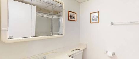 A bathroom with a sink, mirror, toilet, towel rack, and two framed pictures on the wall.