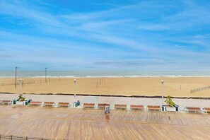A beach with a wooden boardwalk, benches, and a clear sky. - Oceanfront condo on the boardwalk with balcony, central AC, WiFi, & great view (Ocean City)