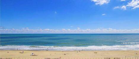 A beach with a clear sky, a sandy shore, and a few people.