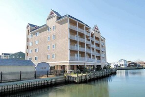 Un hotel de varios pisos con balcones, un muelle y un frente marítimo tranquilo.