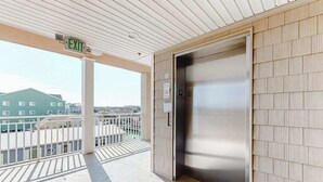 Un ascensor, una señalización de salida y un balcón con vistas a edificios.