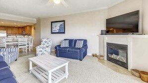 Una sala de estar con chimenea, televisor, comedor y ventilador de techo.
