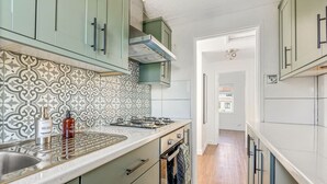 A kitchen with patterned backsplash, a stove, and a sink. - Modern 2-Bed Apartment in Reading (Berkshire)